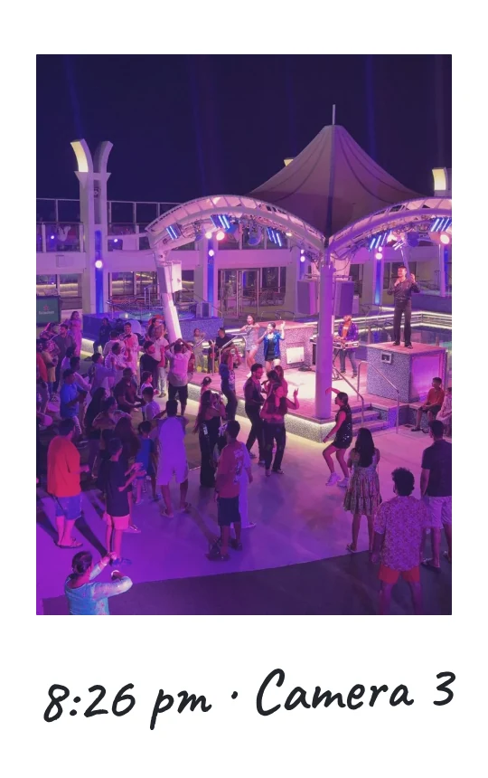 Camera 3, 8:26 pm: a deck party at night, people dancing under purple light