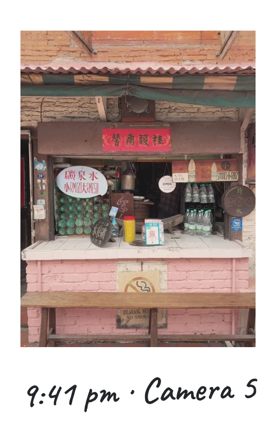 Camera 5, 9:41 pm: a street kiosk with bottled water on display and a hand-painted sign